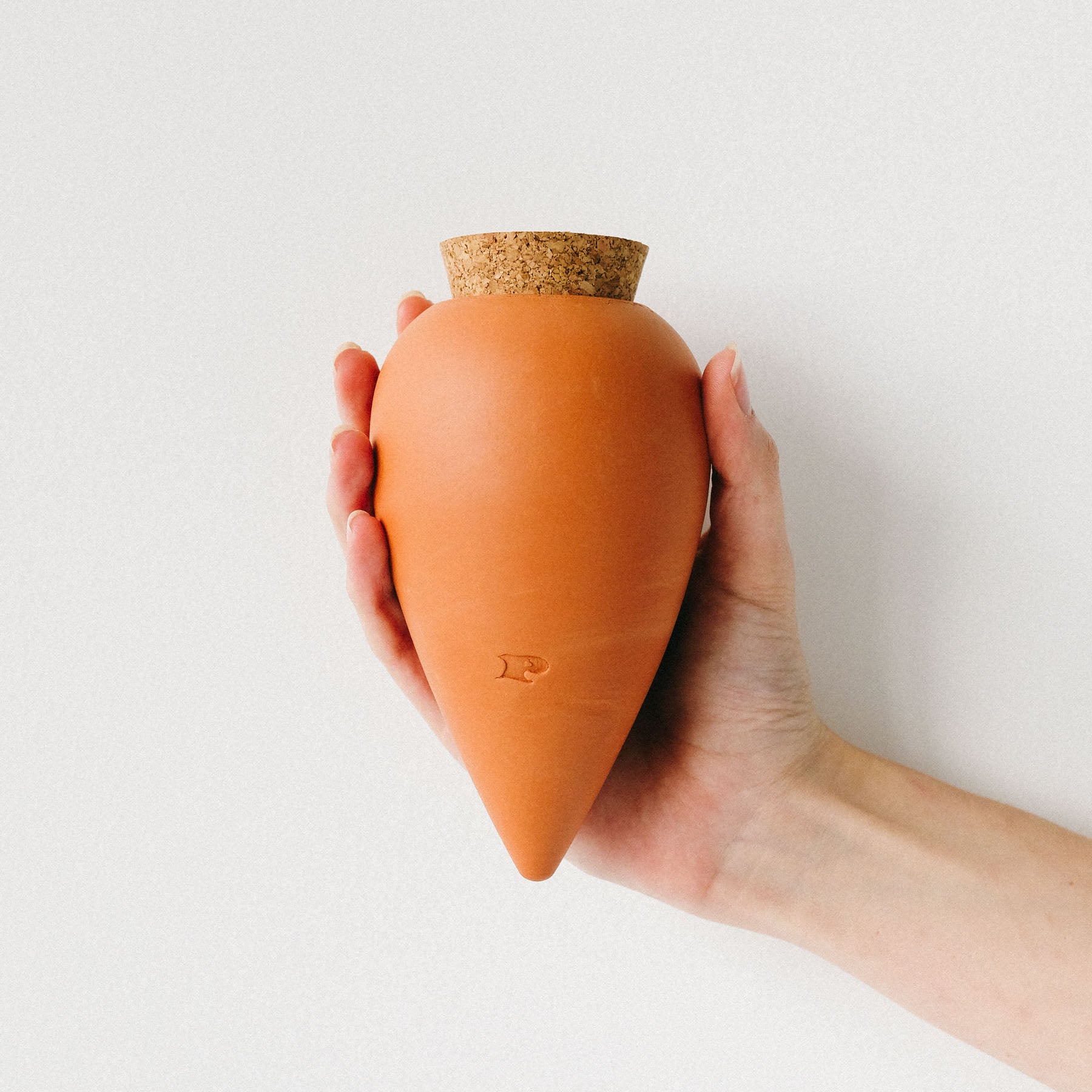 Terracotta farvet Olla, der holdes i en hånd